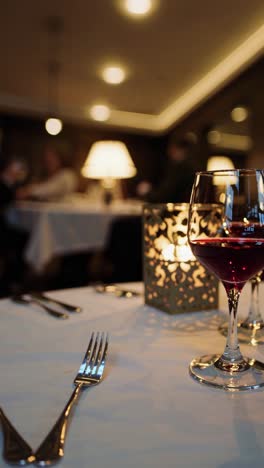 red wine glasses stand on a set table in a softly lit restaurant, creating a romantic ambiance, with subtle camera movement adding a dynamic feel