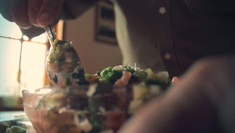 shot from the bottom of chef's hands mixing all the vegetables with a spoon in a bowl