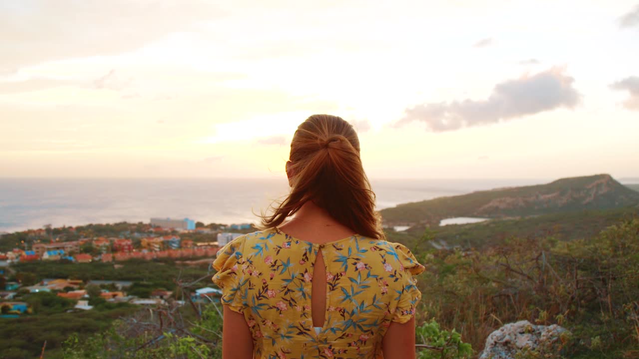 Attractive young woman in a yellow dress looking at the sunset
