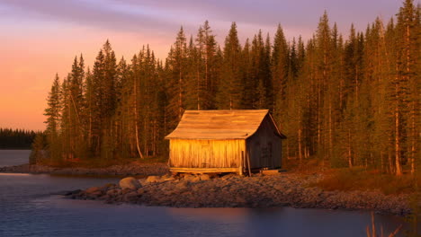 rustic cabin by a lake at sunset