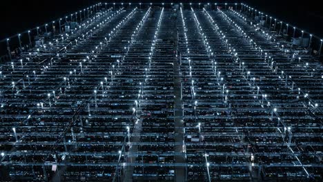 aerial view of a massive warehouse at night: rows of illuminated racks filled with products and equipment, showcasing a modern logistics facility's scale and efficiency