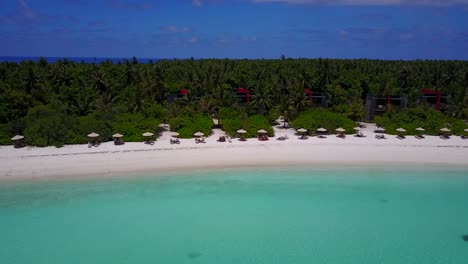panorámica aérea sobre la isla turística de sombrillas en la playa en maldivas en un día pintoresco