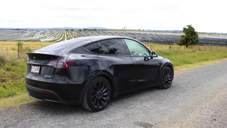 ev car maneuvers into parking by solar panels