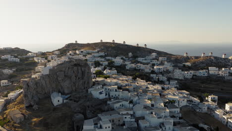 drone shot reveals venetian fortress castle in chora town surrounded by windmills, aegean sea at sunrise, amorgos island, establishing