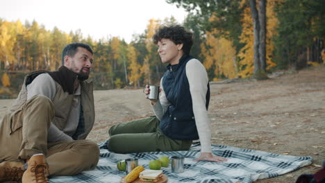couple enjoying a picnic in the autumn forest by the lake