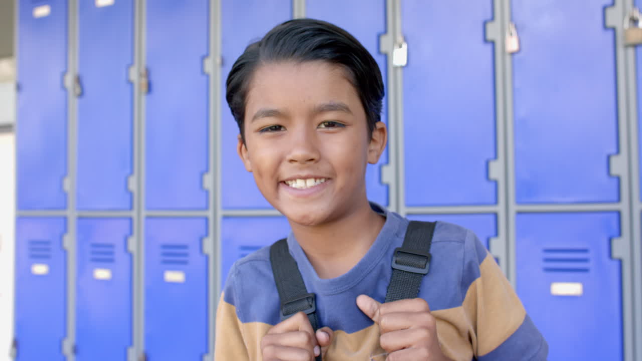 Biracial boy smiles in front of school lockers