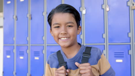 biracial boy smiles in front of school lockers