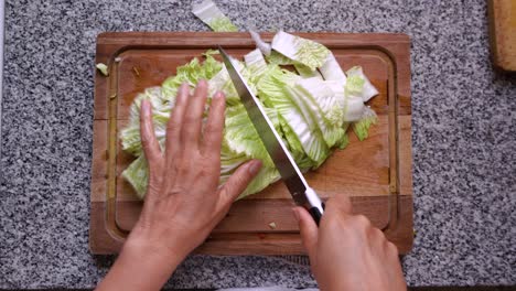 Fotografía-Cenital-De-Un-Cocinero-Cortando-Hakusai-Fresco-En-Una-Tabla-De-Cortar-De-Madera