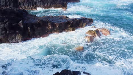 Filmische-Luftenthüllung-Der-Küstenwellen-Von-El-Pris,-Die-Auf-Die-Felsige-Küste-Mit-Dem-Vulkan-El-Teide-Im-Hintergrund-Von-Teneriffa,-Kanarischen-Inseln,-Spanien-Krachen