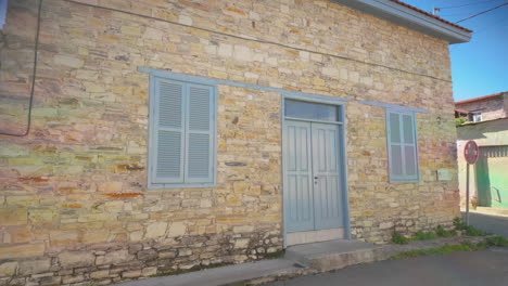 stone house with blue shutters and a matching door, set against a bright blue sky