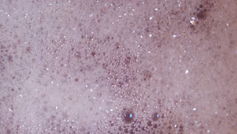 close up top view of foam and soapy bubbles on a moving water surface, self care, bathtub, pink background