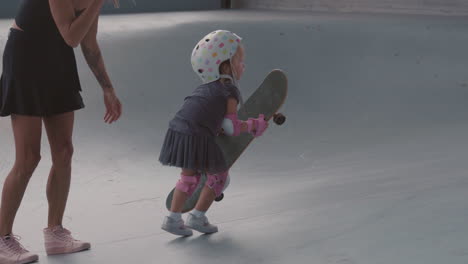 mother helping child skateboarding