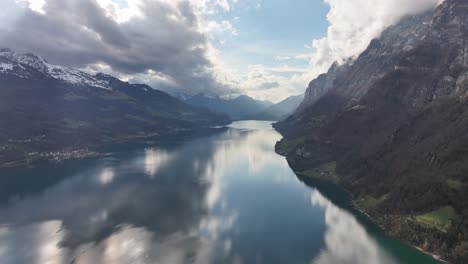 aerial of large lake between two mountains resting in clouds