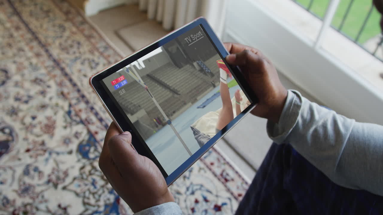 Composite of man sitting at home, watching athletics high jump event on tablet