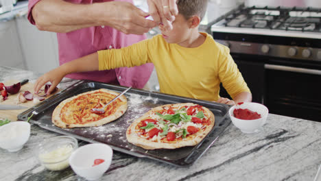 Feliz-Abuelo-Caucásico-Y-Nieto-Haciendo-Pizza-En-La-Cocina,-Cámara-Lenta