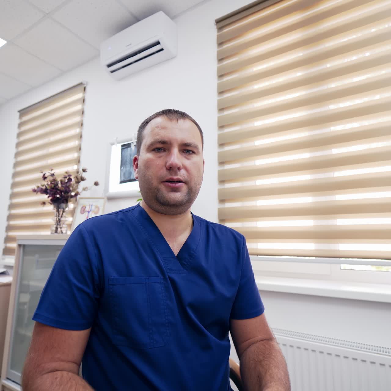Remote consultation during pandemic. Professional doctor sitting in medical center and talking on camera. Portrait of male medical specialist in clinic.