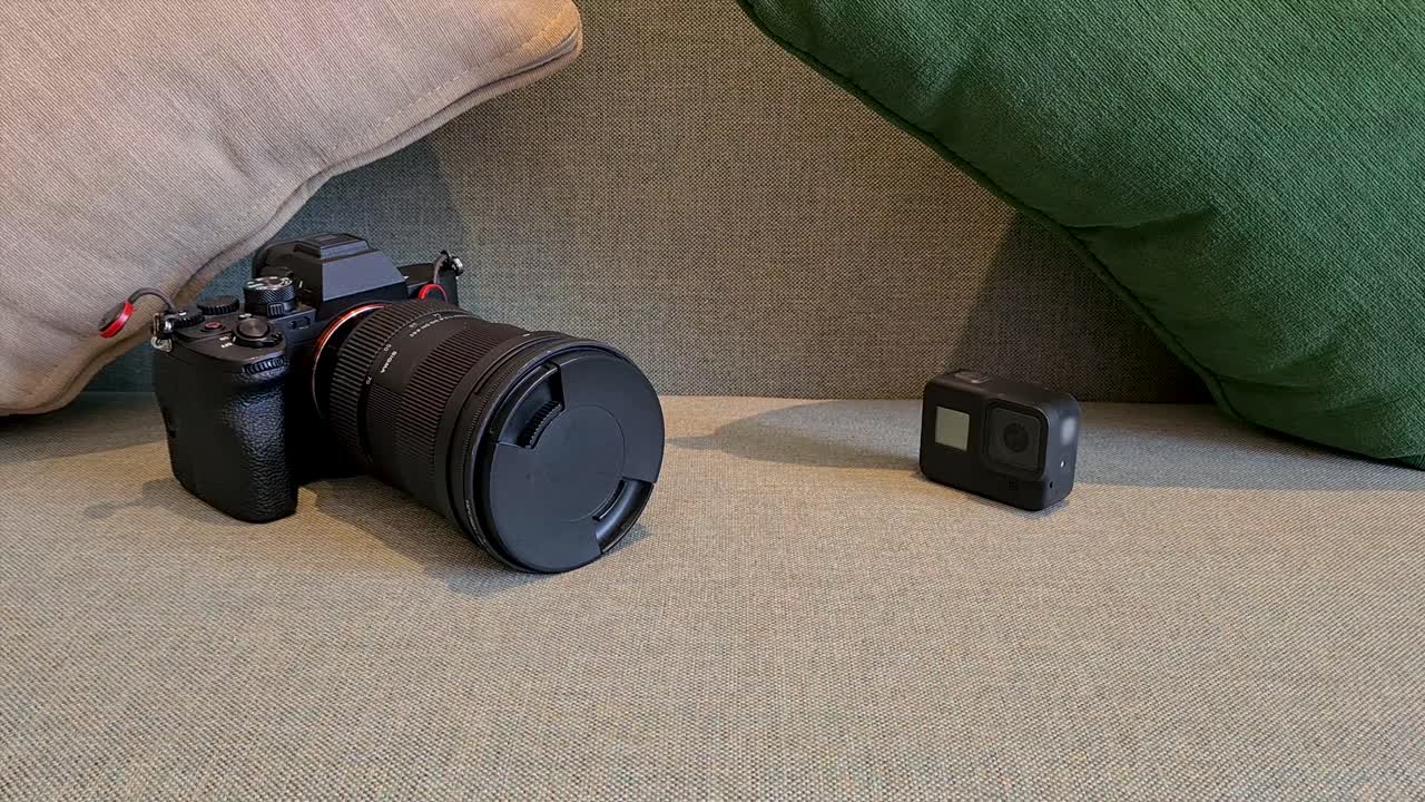 Mirrorless camera and an action camera sit on a sofa for a clean product display shot, ideal for technology, photography gear, video equipment and consumer electronics themes