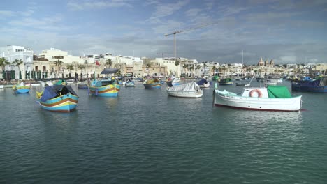 panoramic view of marsaxlokk bay with lots of beautiful small boats rocking in the water