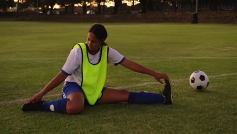 female soccer player stretching her legs on soccer field. 4k