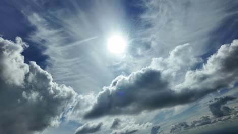 a dramatic and dynamic cloudscape as seen from the pilot of an airplane while flying under a dramatic sky full of scattered clouds and sun rays piercing the clouds