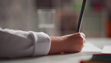 Little-child-draws-picture-on-paper-with-pencil-at-table