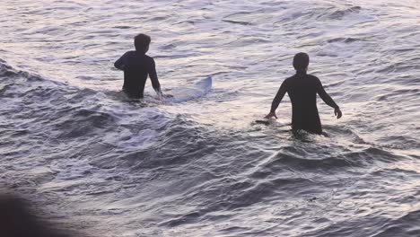 a young two surfers are going into the ocean holding their surfboards