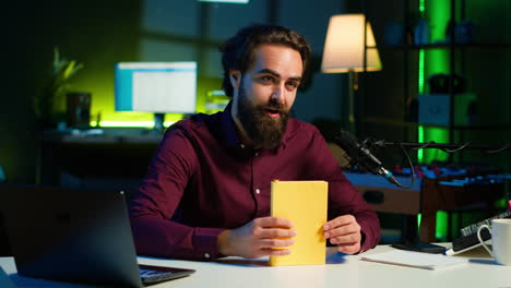 creador de contenido alegre en el estudio revisando un libro de tapa dura recién lanzado