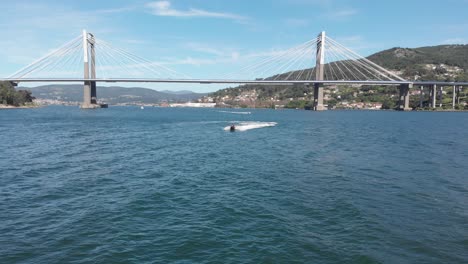 jet ski makes its way past the puente de rande, rande bridge located in the city of vigo, galicia, spain