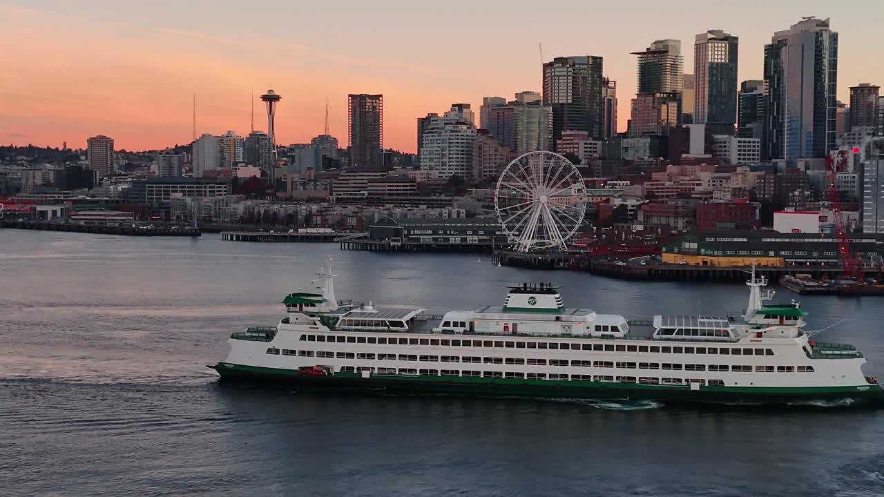 The Bainbridge ferry glides into Seattle as sunrise reflects on the water