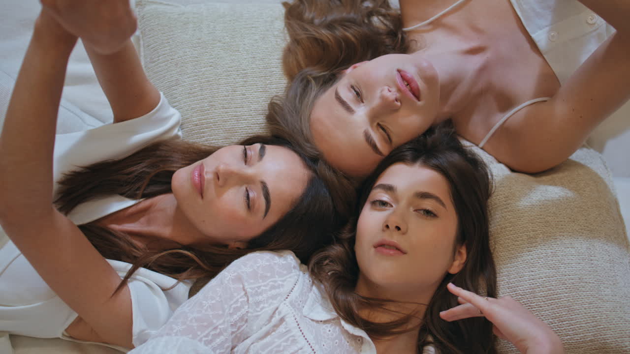 아름다운 여성들이 함께 누워있는 클로즈업. 상단 뷰 평화로운 소녀들이 부드럽게 만지고 있습니다.