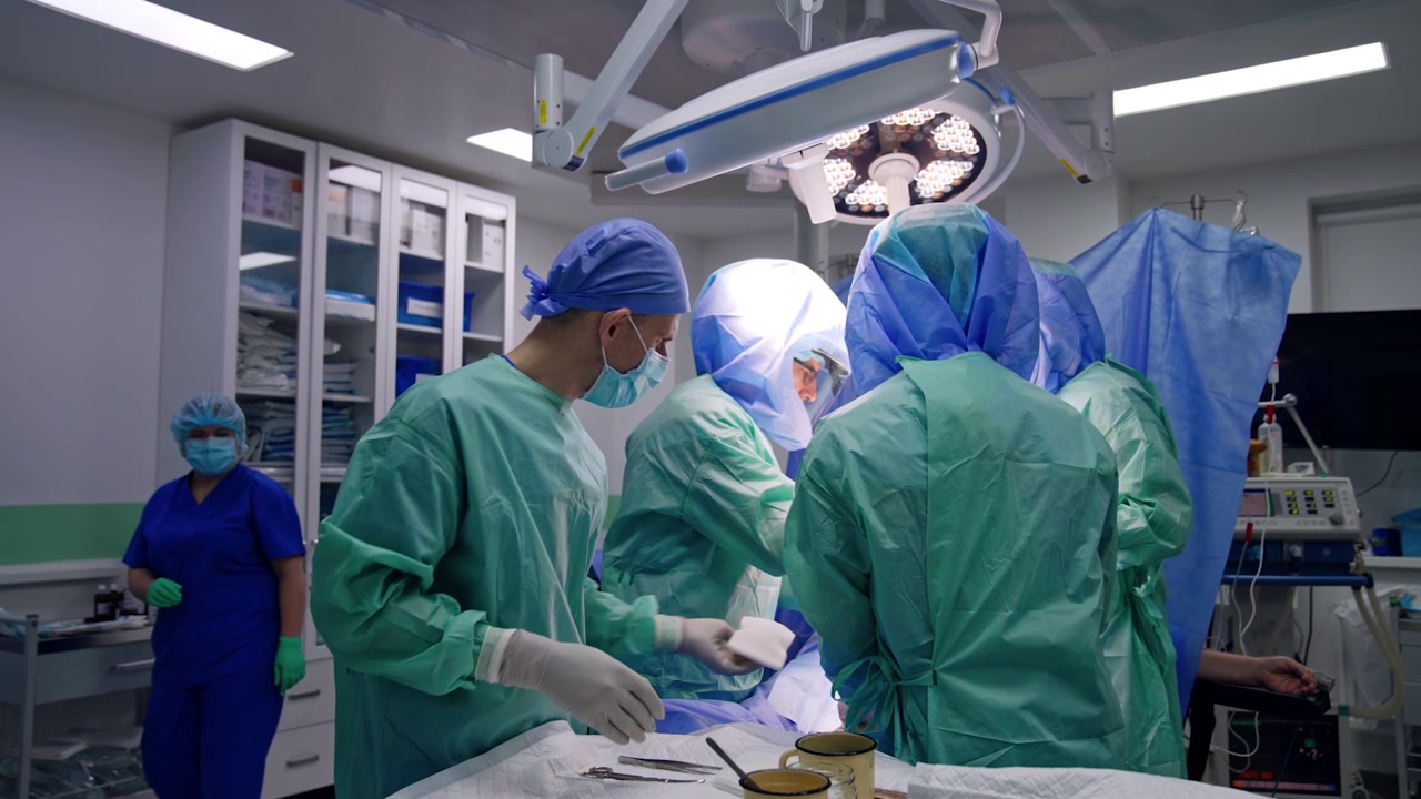 Equipe medica che lavora durante un'operazione in sala operatoria. Medici con caschi protettivi eseguono la procedura su un trauma.