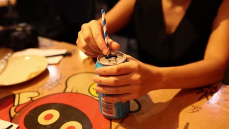 person inserting straw into a beverage can