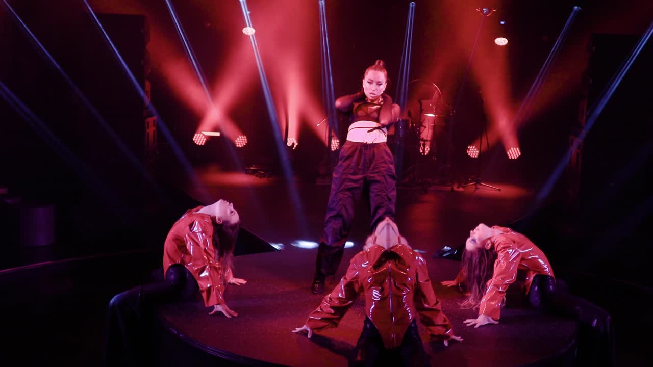 в клубе, медленные движения камеры на стабилизаторе захватывают четырех танцоров, выступающих под концертным освещением