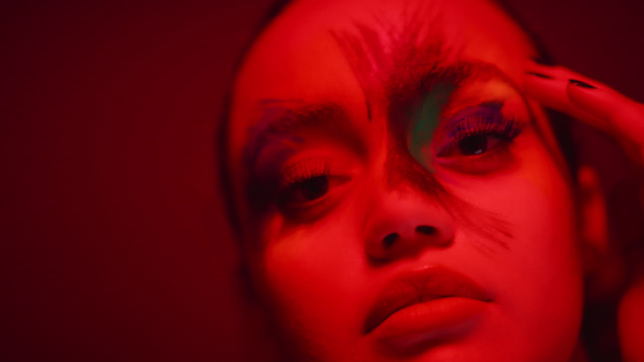 ritratto colorato ravvicinato donna attraente che indossa vernice per il viso fluorescente arte del corpo multicolore esotica con luce ultravioletta lampeggiante concetto di trucco estremo