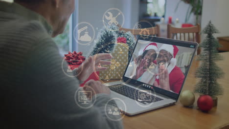Video calling couple in Santa hats, man using animation with digital icons