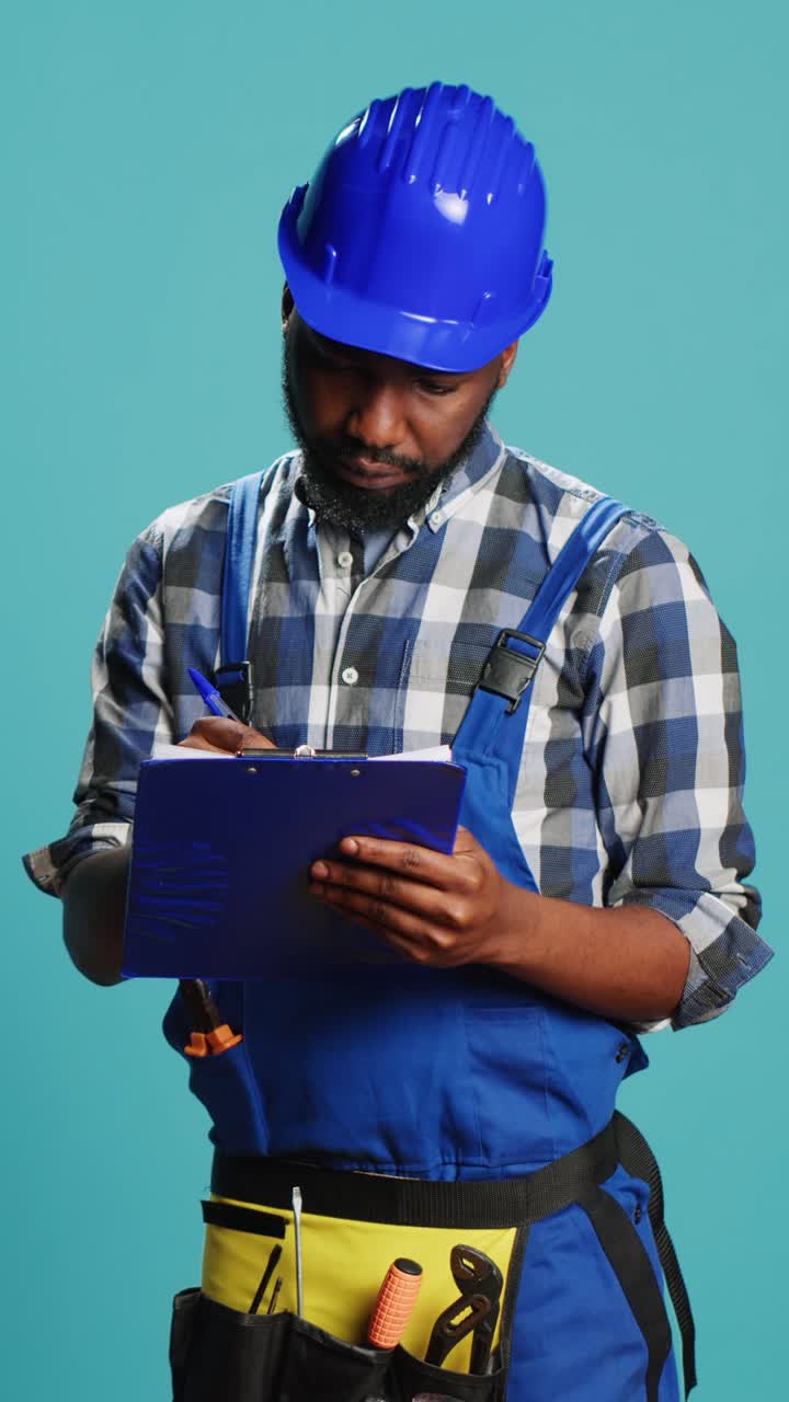 Vertical video: Young handyman making calculations on files