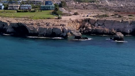 aerial drone shot of a rocky sea coast with a tourist resort in the background