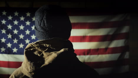 The-Silhouette-Of-A-Man----He-Looks-At-The-American-Flag-On-The-Brick-Wall-The-View-From-Behind