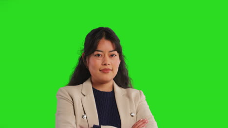 Close-Up-Studio-Portrait-Of-Female-Teacher-Or-Businesswoman-Standing-Against-Green-Screen-Folding-Arms