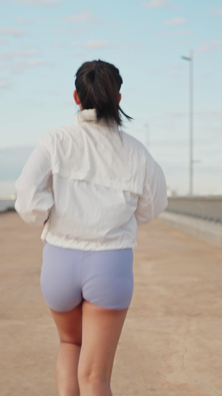 Giovane donna che corre all'aperto su un percorso asfaltato.