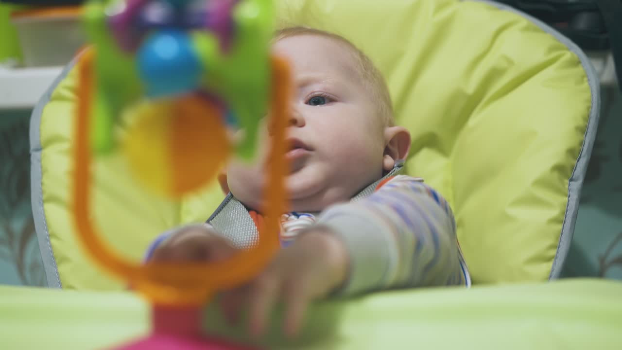 criança pequena brinca com brinquedo engraçado em cadeira alta macia moderna