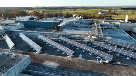 Solar-panels-and-smokestacks,-HVAC-units-on-industrial-office,-factory-rooftop-in-USA