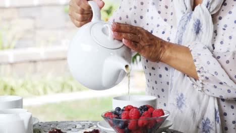 mujer madura vertiendo té de limón en una taza 4k