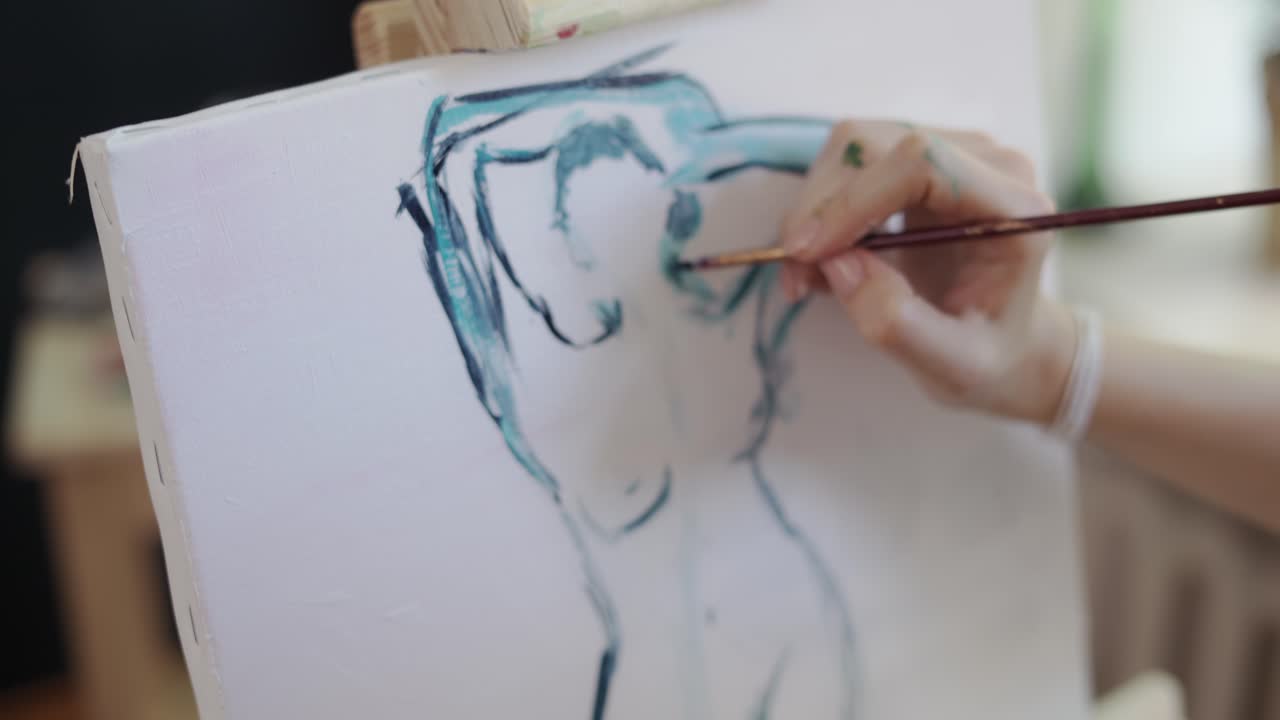 여성 예술가가 팔레트에 페인트를  ⁇ 어서 캔버스에 여성 몸을 그립니다.