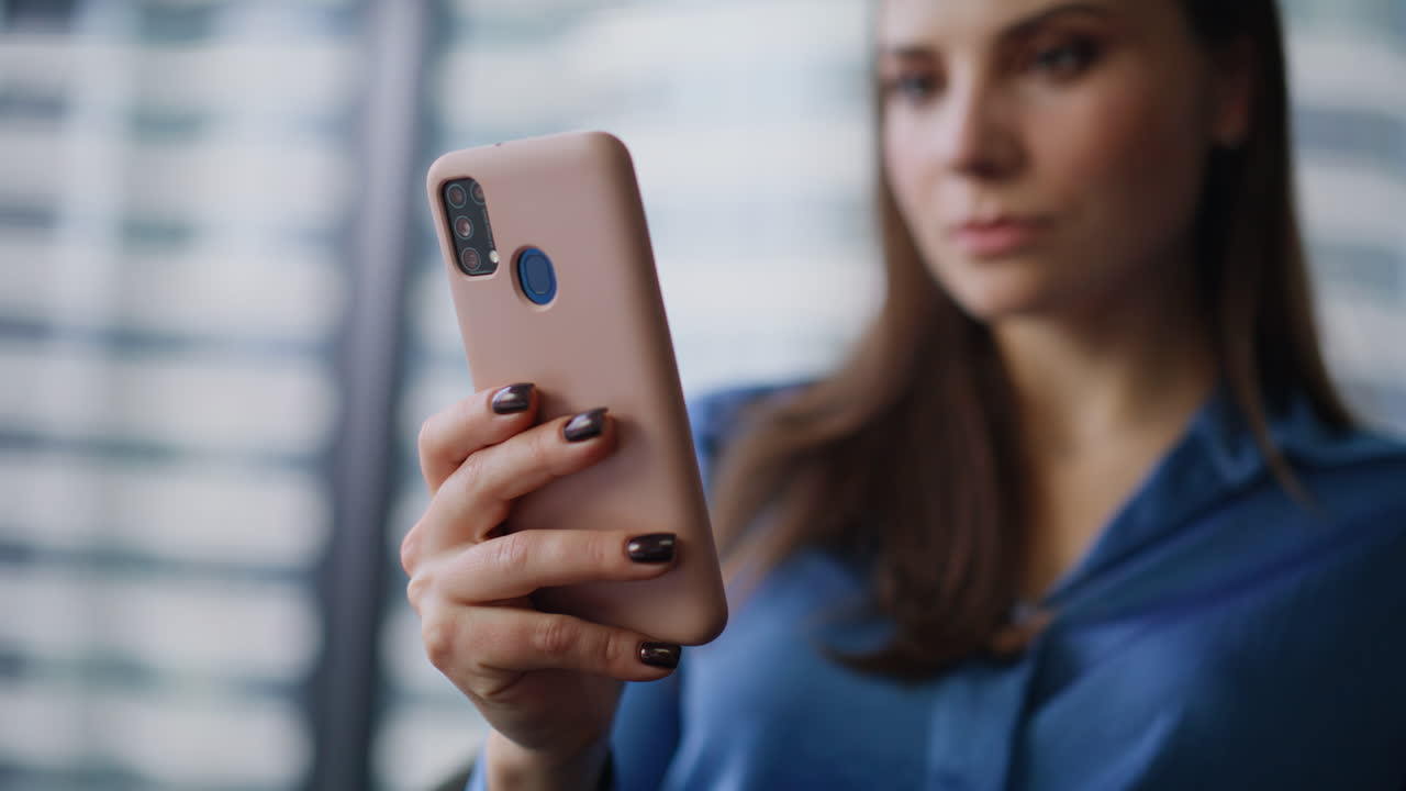 Elegant brunette tapping cellphone making online purchase in office closeup