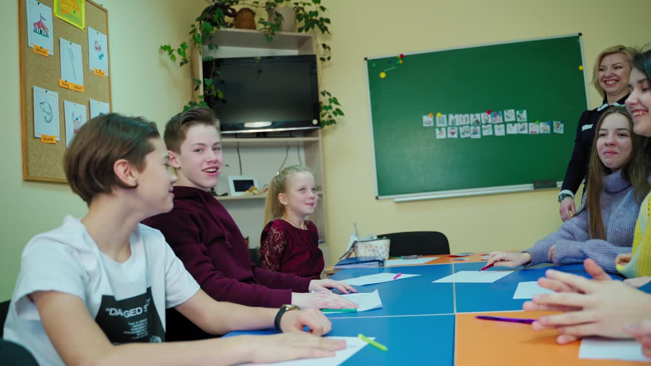 Active students in the classroom. Teen children are putting hands together on the table in the middle school class. Friendly classmates having fun at school.