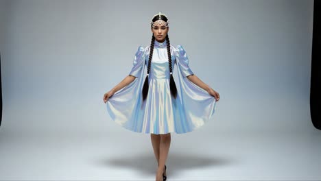 an elegant fashion model showcases a shimmering holographic dress paired with a stunning pearl-adorned headpiece, exuding grace and sophistication in a chic studio setting