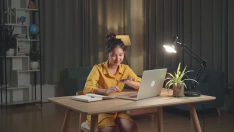 asia woman with laptop computer calling on smartphone from home at night
