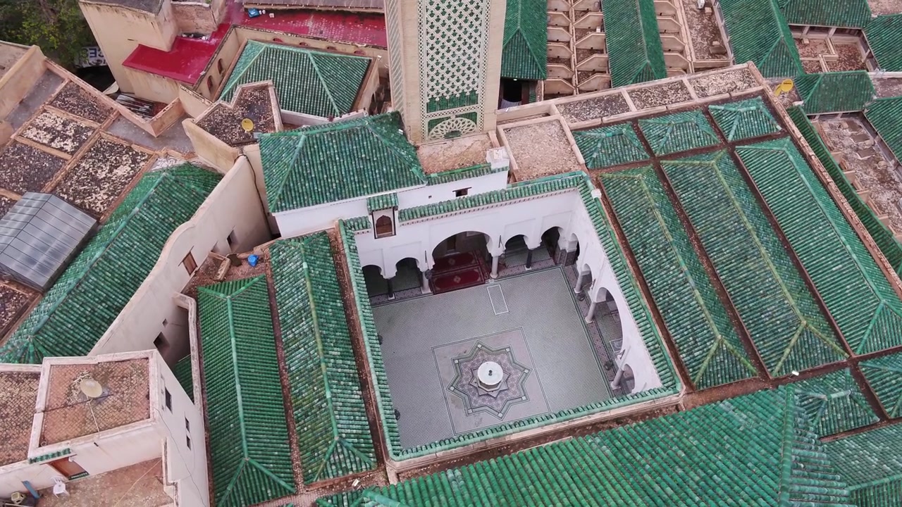 Vista aerea ravvicinata con drone del cortile della Moschea Al Quaraouiyine, con tetti di tegole verdi e storica architettura islamica nella Medina di Fez, Marocco, ideale per progetti culturali.