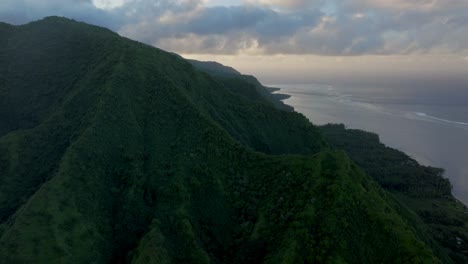 Teahupoo-Tahiti-across-mountain-peaks-valley-hills-jungle-coastline-sunrise-yellow-clouds-golden-hour-sunset-aerial-drone-view-French-Polynesia-WSL-Surfing-summer-Olympic-venue-town-village-forward